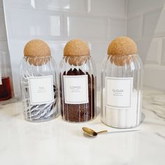 three jars filled with different types of spices on a counter top next to spoons