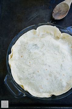 an uncooked pie sitting on top of a table next to a spoon