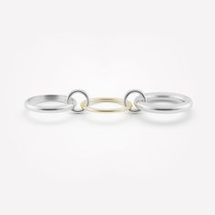 The Amaryllis features a palette of multi-gauge rings, with two full round bands framing a half-round. All three bands are joined by a pair of floating sterling silver connectors, enabling the ring to be worn as a single piece or across multiple fingers as a modular design. Each Amaryllis is individually handmade in Los Angeles. White Gold Stackable Oval Rings, Modern Silver Oval Link Ring, Modern Jewelry With Interchangeable Round Pieces, Modern Interchangeable Round Jewelry, Timeless White Gold Hoop Rings, Modern Sterling Silver Bands, Elegant Sterling Silver Full Circle Ring, Elegant Full Circle Sterling Silver Rings, Elegant Full Circle Jewelry With Ring Detail