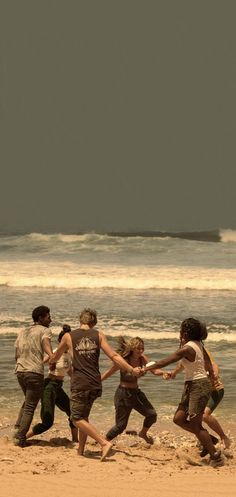 four people running on the beach holding hands