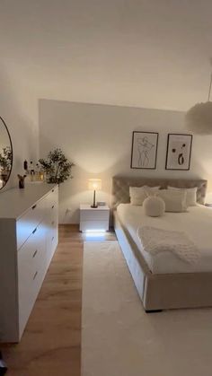 a large white bed sitting in the middle of a bedroom