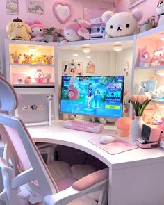 a white desk topped with a computer monitor next to a pink chair and shelves filled with stuffed animals