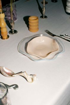 a table topped with dishes and utensils on top of a white table cloth