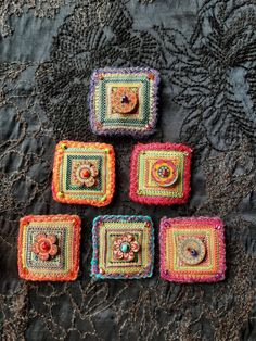 four square crocheted coasters on a lace tablecloth with beads and buttons