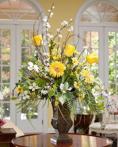 a vase filled with yellow flowers on top of a wooden table