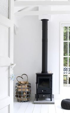 a black stove sitting in the corner of a room next to a basket and door