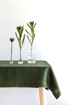 three vases with flowers are sitting on a tablecloth that has been placed on it