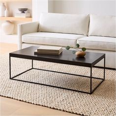 a black coffee table sitting on top of a rug next to a white couch in a living room