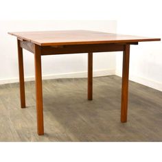 a wooden table sitting on top of a floor next to a white wall and hardwood floors