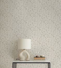 a table with a lamp on top of it next to a wallpapered wall