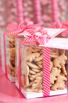 two boxes filled with cookies sitting on top of a pink table covered in candy canes