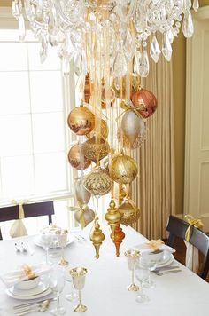 a chandelier hanging from the ceiling over a table with place settings on it