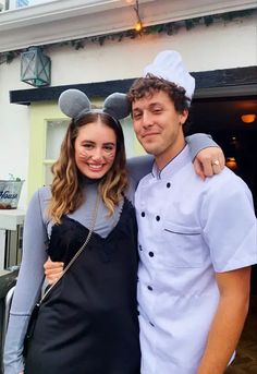 a man and woman are posing for a photo in front of a restaurant with mickey ears on their heads