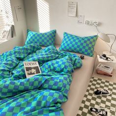 a bed with blue and green checkered comforter on top of it next to black and white checkered rugs