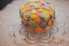 a decorated cake sitting on top of a glass plate covered in confetti dots