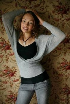 a young woman posing for a photo in front of a floral wall with her hands on her head