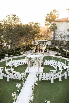 an outdoor ceremony setup with white chairs and flowers