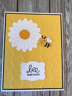 a card with a flower and a bee on it, sitting on top of a wooden table