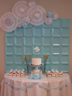 a cake and cupcakes on a table with blue wall paper decorations behind it