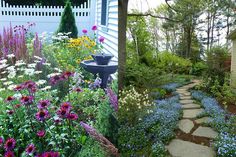 a garden filled with lots of flowers next to a house