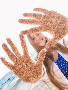 a girl holding up her hands covered in sand