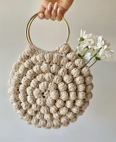 a crocheted purse with a flower in the middle and a hand holding it