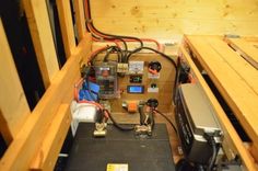 the inside of a wooden box with various electrical equipment and wires on top of it