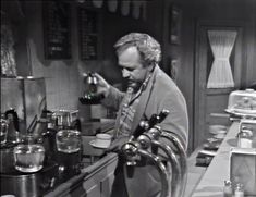 a man pouring something into a glass in a kitchen