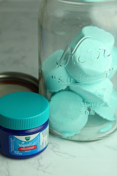 a jar filled with blue and green marshmallows sitting on top of a counter