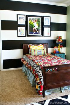 a bedroom decorated in black and white stripes with a bed, dresser, pictures on the wall