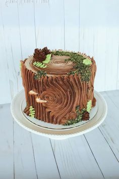 a cake that is sitting on top of a white plate and has green leaves around it