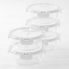 four clear plastic containers with lids on a white surface