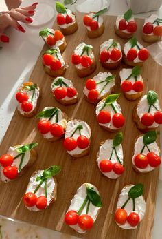 small appetizers with cherry tomatoes and cream cheese are on a wooden cutting board