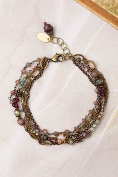 A stylish multistrand design, handcrafted with collage strands for a unique look. Antique Brass (lead and nickel free) Crystal, Lepidolite Quartz, Czech Glass 7.5-8.5", adjustable with an antique brass lobster claw clasp We hand select our natural materials, thus there may be slight variations in color and/or size that will not detract from the overall aesthetic Our unique handcrafted designer jewelry for women is made in America, with each design created individually in our personal design studio in Floyd VA USA Bohemian Bracelets With Extender, Bohemian Adjustable Bracelets With Extender, Bohemian Brass Bracelets With Adjustable Chain, Bohemian Metal Beaded Bracelets With Adjustable Chain, Nickel-free Adjustable Multi-strand Bracelets, Adjustable Multicolor Brass Bracelets, Bohemian Bracelets With Adjustable Chain, Bohemian Multi-strand Wire Wrapped Beaded Bracelets, Adjustable Multi-strand Brass Jewelry