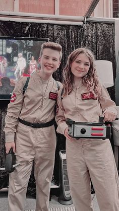 two young boys dressed in uniforms standing next to each other with a camera on their laps