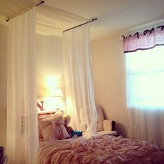 a bed with white drapes hanging from it's sides