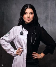 a woman with a stethoscope standing in front of a gray background wearing a white coat