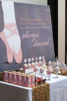 a table topped with cupcakes and cakes next to a sign