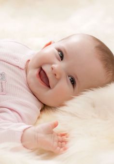 a smiling baby laying on top of a white rug