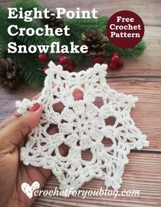 a crochet snowflake is shown with pine cones in the background