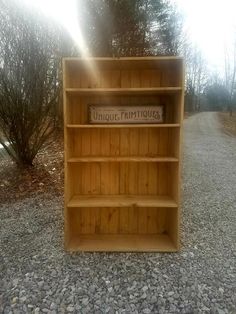 a wooden book shelf sitting on top of a gravel road