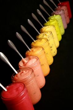 a row of small jars filled with different colored liquids and spoons sticking out of them