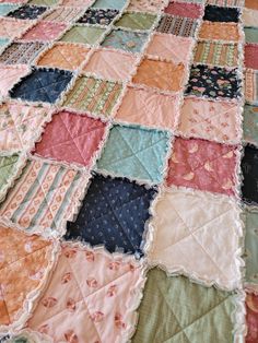 an old quilt is laying on top of a tablecloth that has been made into a blanket