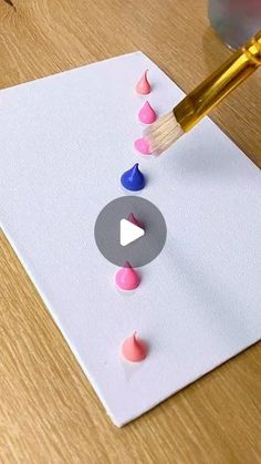 someone is painting something on the paper with colored paint and a brush that has been placed in front of it