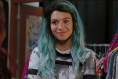 a woman with green hair and blue eyes is looking at the camera while she's smiling