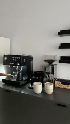 there is a coffee maker and two cups on the counter next to each other in this room