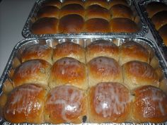 two trays filled with rolls covered in frosting