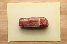 a piece of bacon sitting on top of a cutting board next to a yellow paper