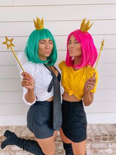 two women dressed up in costumes and holding wands, one with green hair and the other pink