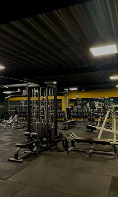 an empty gym with rows of machines and weight benches in the middle of the room